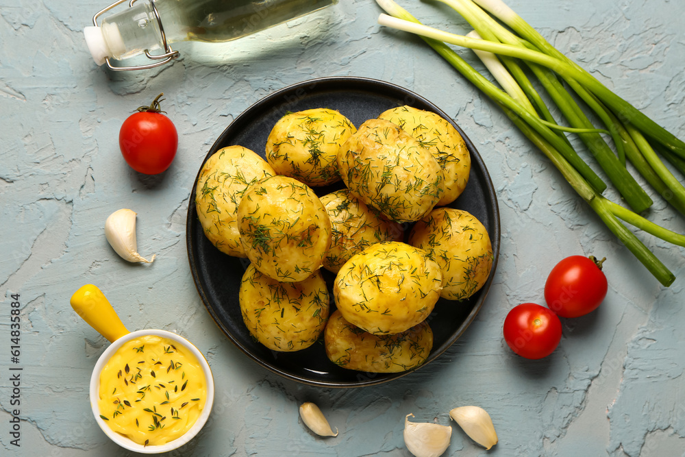 Plate of boiled baby potatoes with dill and sauce on blue background