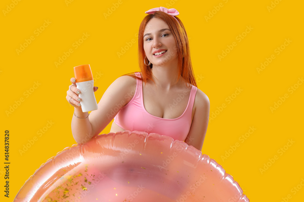 Young woman with sunscreen cream and inflatable ring on yellow background