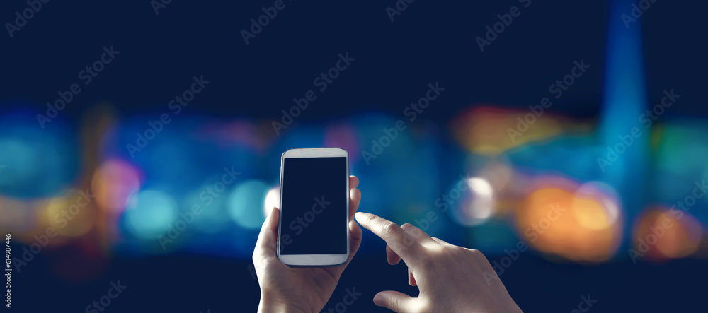 Person using a smartphone in a city at night