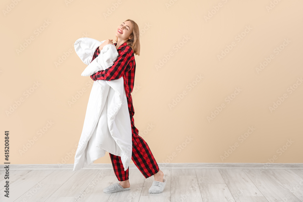 Young woman in pajamas with blanket near beige wall