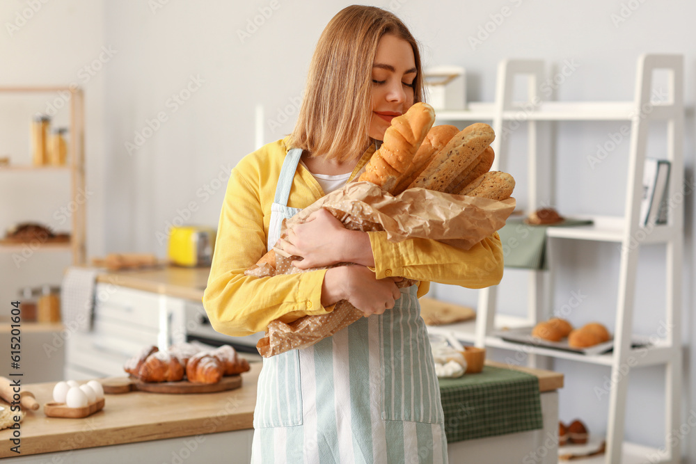 Female baker with fresh baguettes in kitchen