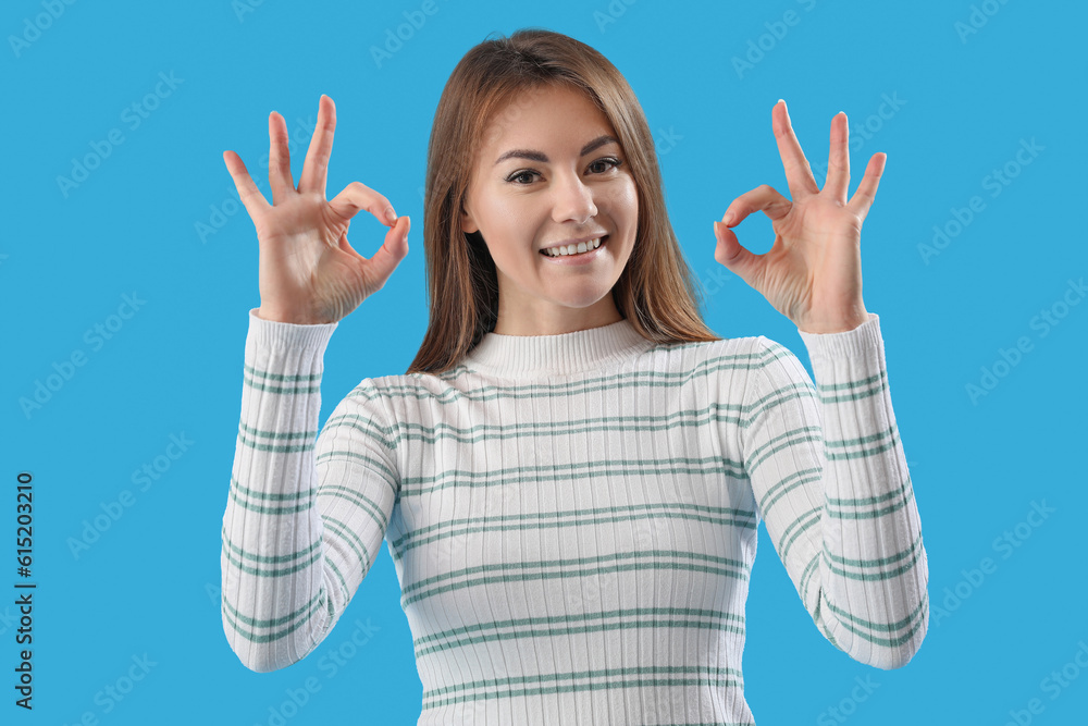 Beautiful woman showing OK on blue background