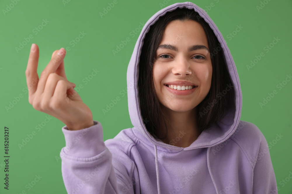 Beautiful young woman snapping fingers on green background, closeup