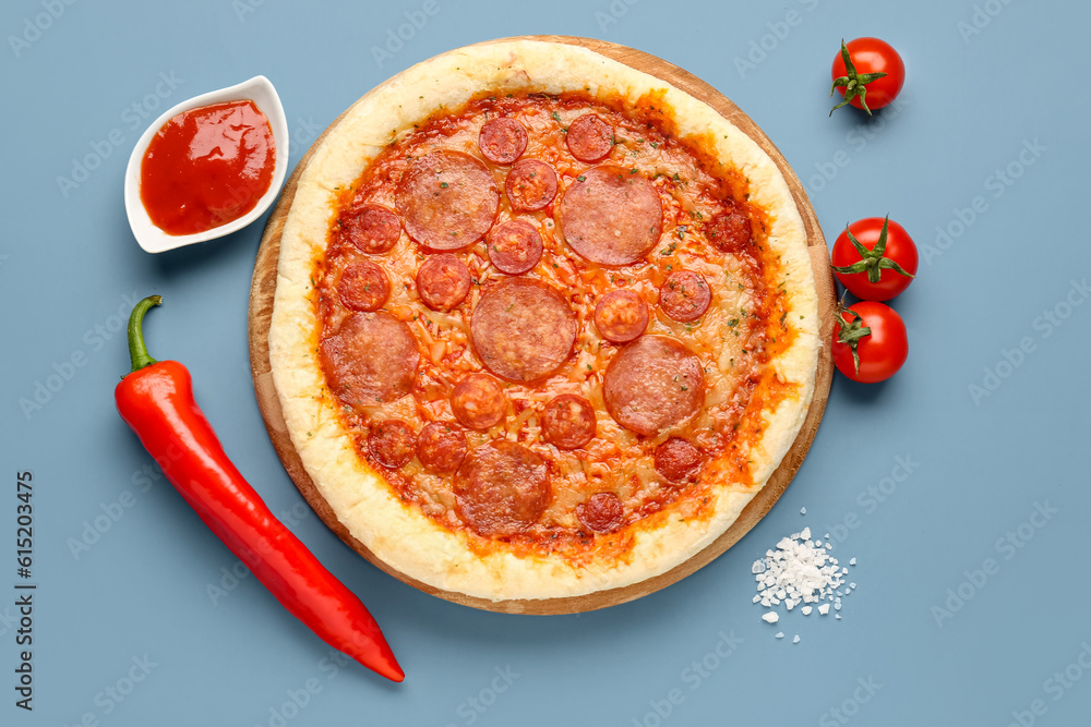 Delicious pepperoni pizza, tomatoes, jalapeno pepper and sauce on blue background