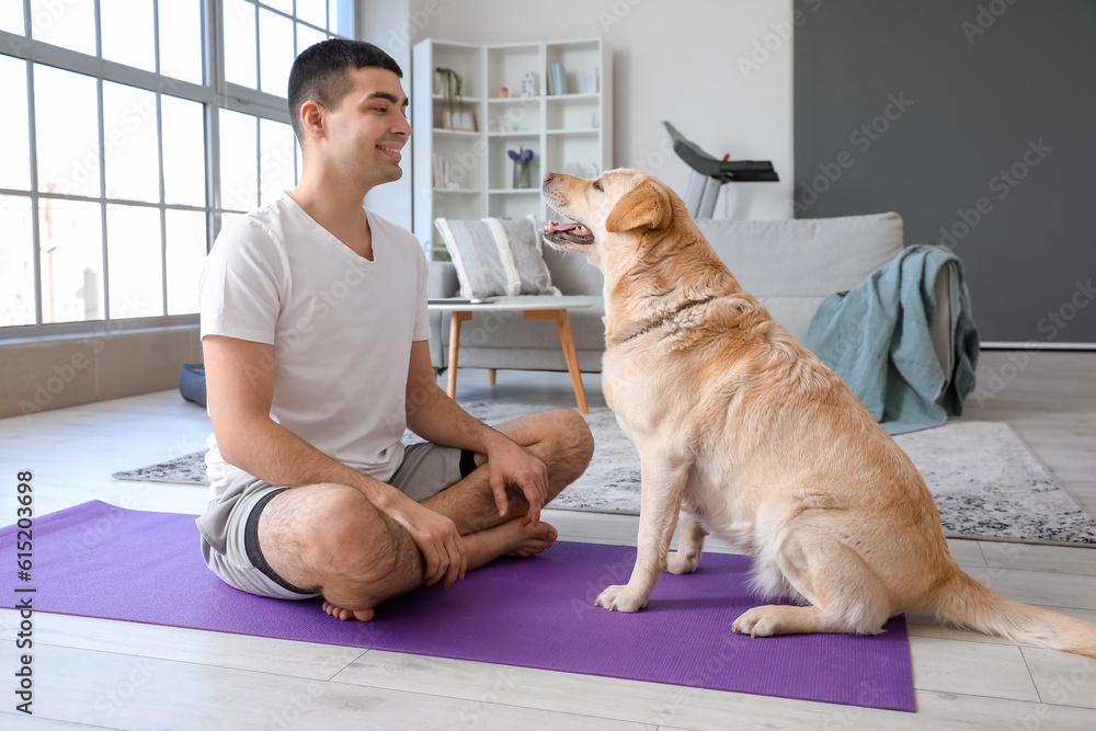 Young man with cute Labrador dog training at home