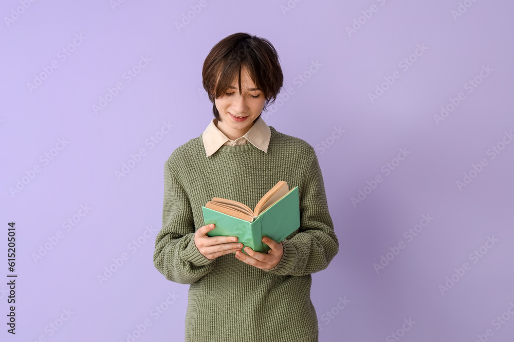 Teenage boy reading book on lilac background