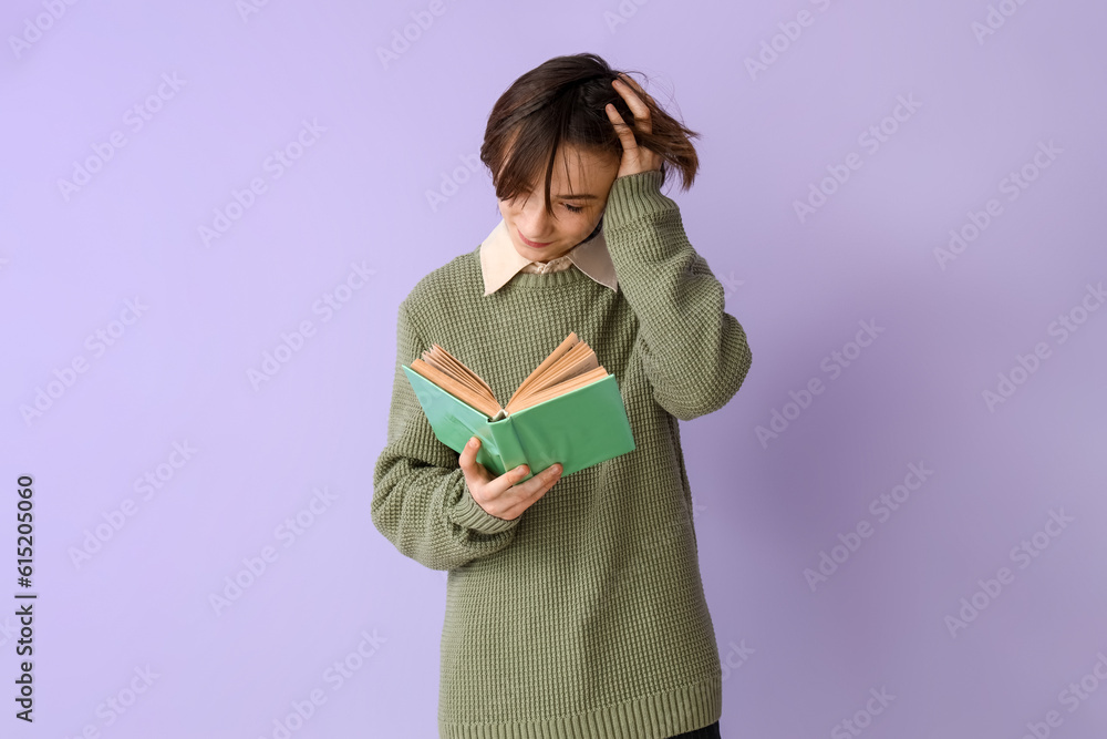 Teenage boy reading book on lilac background