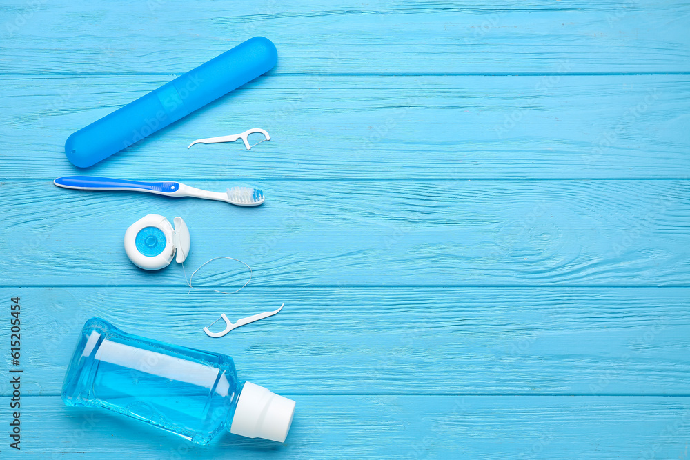 Dental floss, rinse, toothpicks and brush on blue wooden background