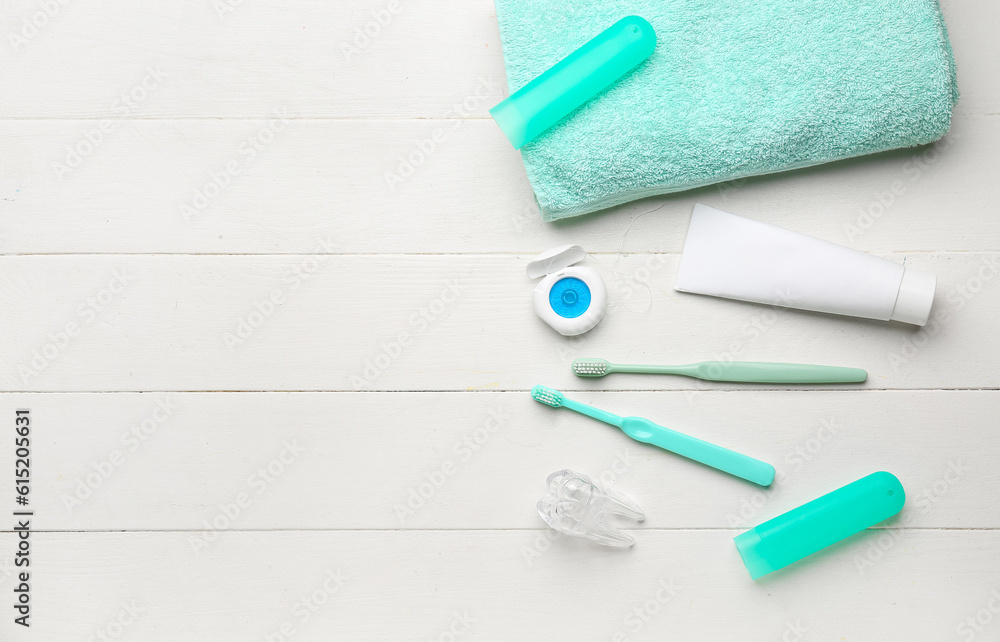 Composition with dental floss, brushes, toothpaste and rinse on white wooden table