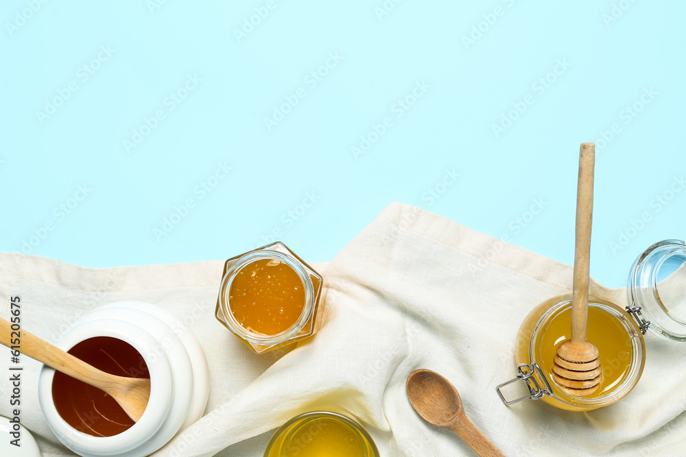 Jars and bowls with sweet honey on blue background