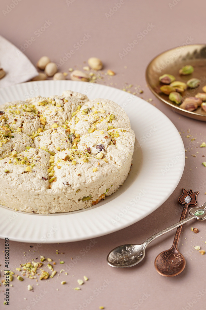 Plate of tasty Tahini halva with pistachios on beige background, closeup