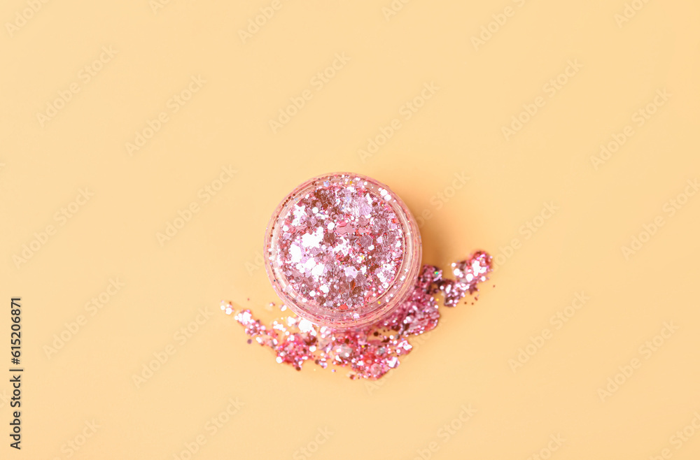 Jar of pink glitter on beige background