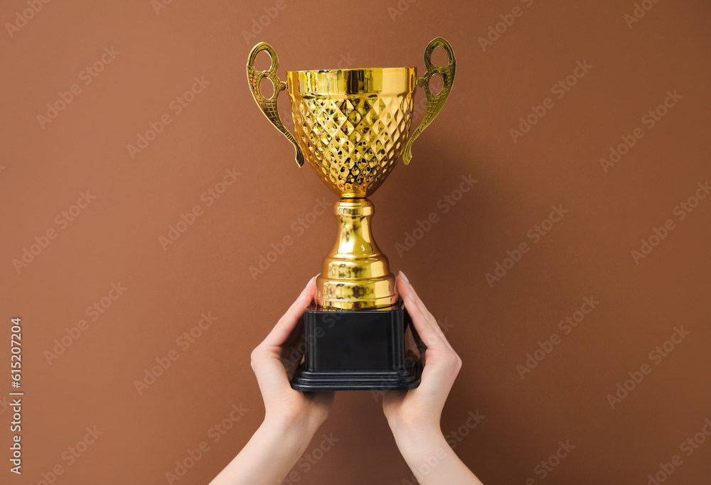 Woman with gold cup on brown background