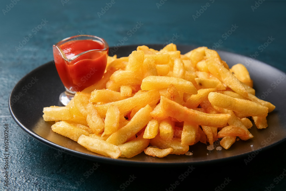 Plate with tasty french fries and ketchup on dark color background, closeup