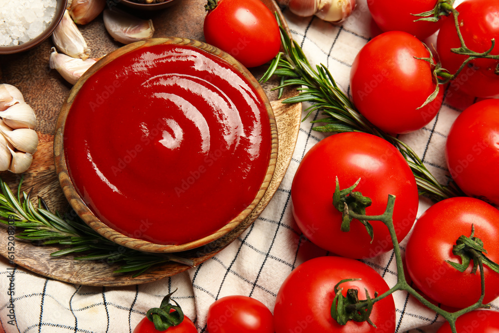 Bowl with tasty ketchup and fresh vegetables on table, closeup