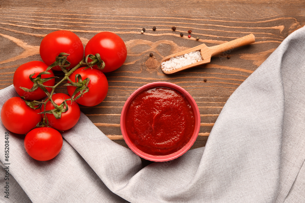 Bowl with tasty tomato paste and fresh vegetables on wooden background