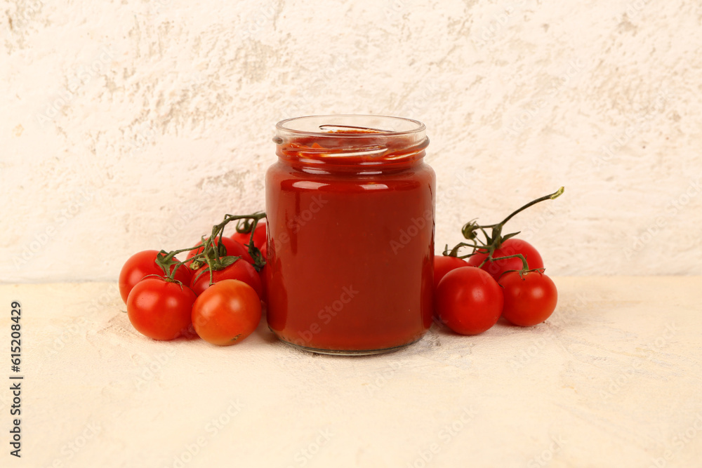 Jar with tasty tomato paste and fresh vegetables on light background