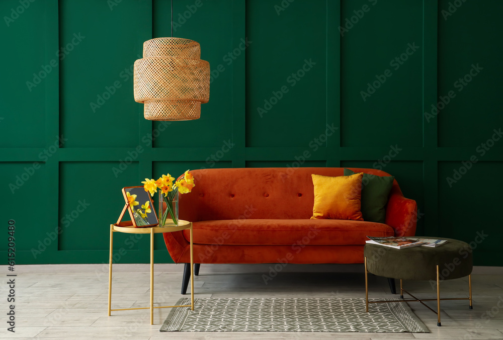 Interior of living room with brown sofa, coffee table and pouf near green wall