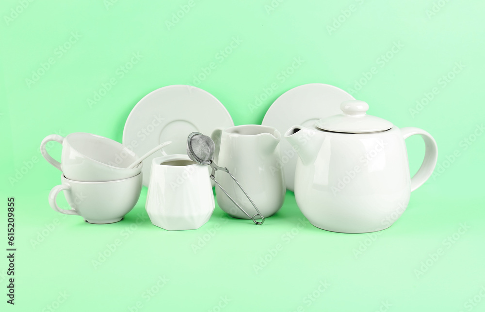 Stylish tea set on green background