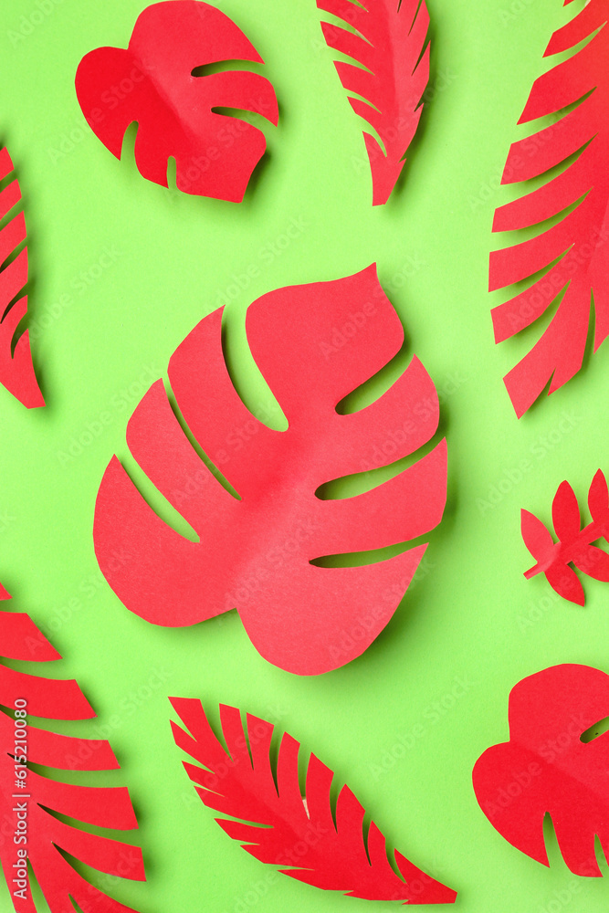 Red paper tropical leaves on green background