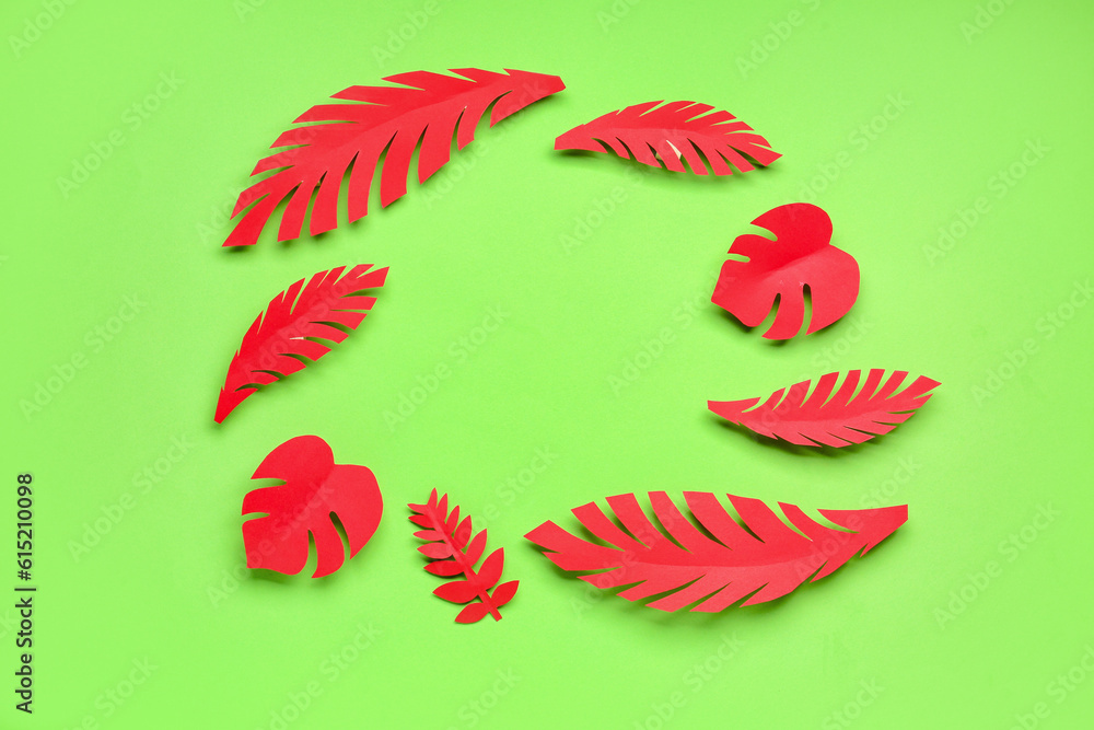 Frame made of red paper tropical leaves on green background