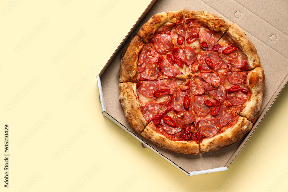 Cardboard box with delicious pepperoni pizza on beige background