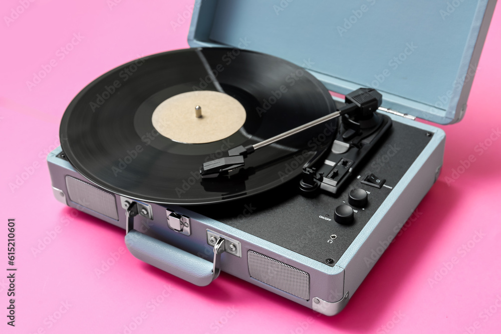 Record player with vinyl disk on pink background, closeup