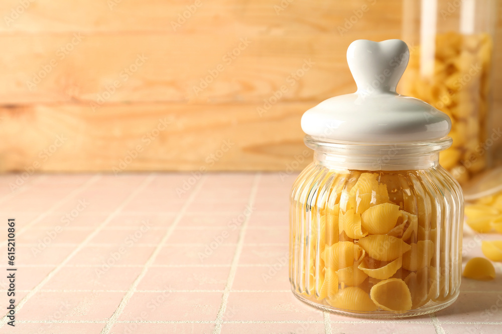 Jar with raw conchiglie pasta on table