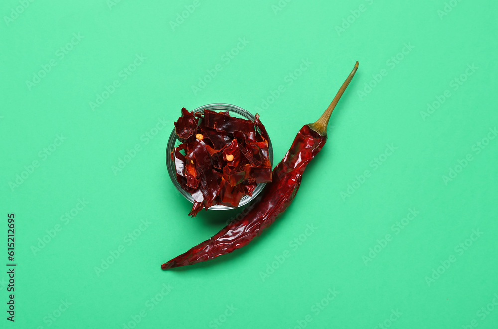 Bowl with sliced chili pepper on green background