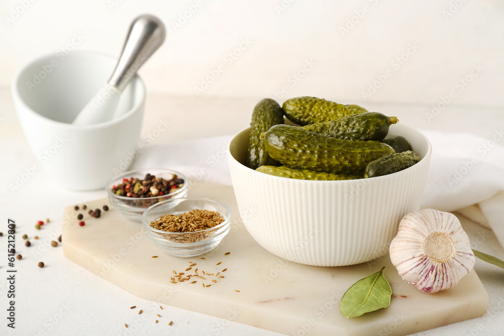 Mortar and board with bowl of canned cucumbers on white table