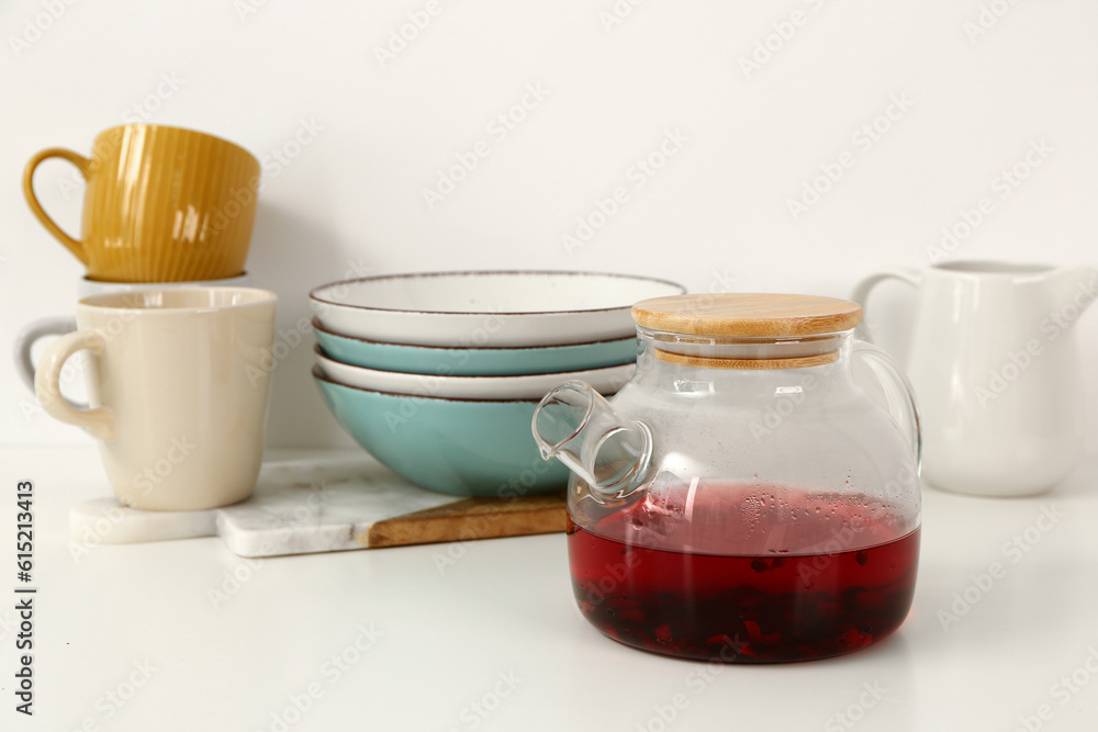 Composition with glass teapot and different kitchen utensils on white table