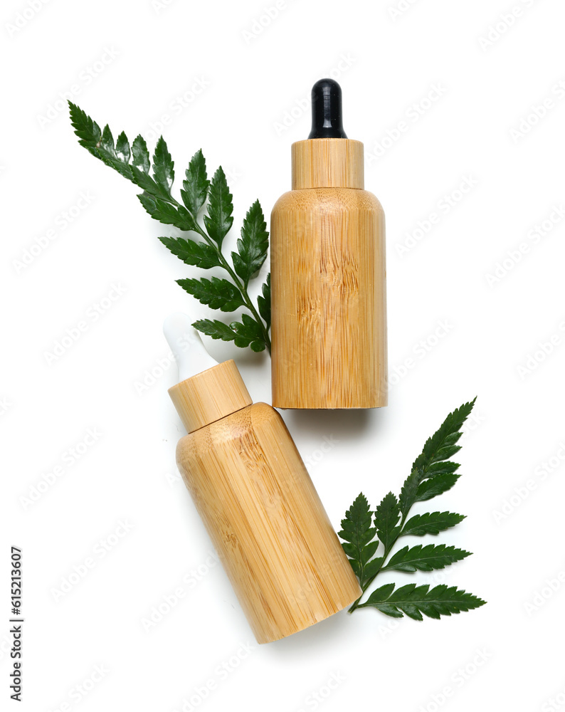 Bottles of cosmetic oil with plant twig on white background