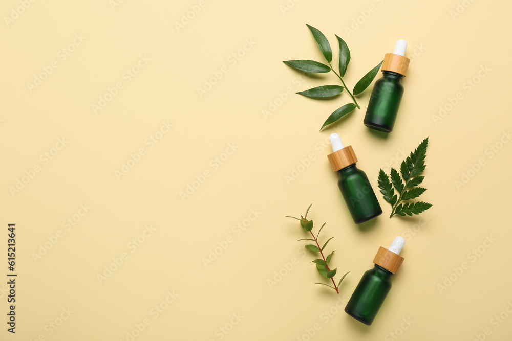 Bottles of cosmetic oil with plant twigs on beige background