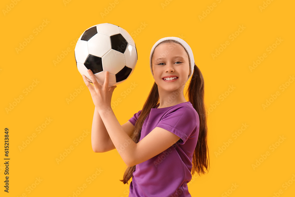 Sporty little girl with soccer ball on yellow background