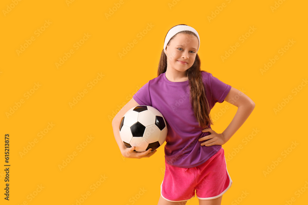 Sporty little girl with soccer ball on yellow background