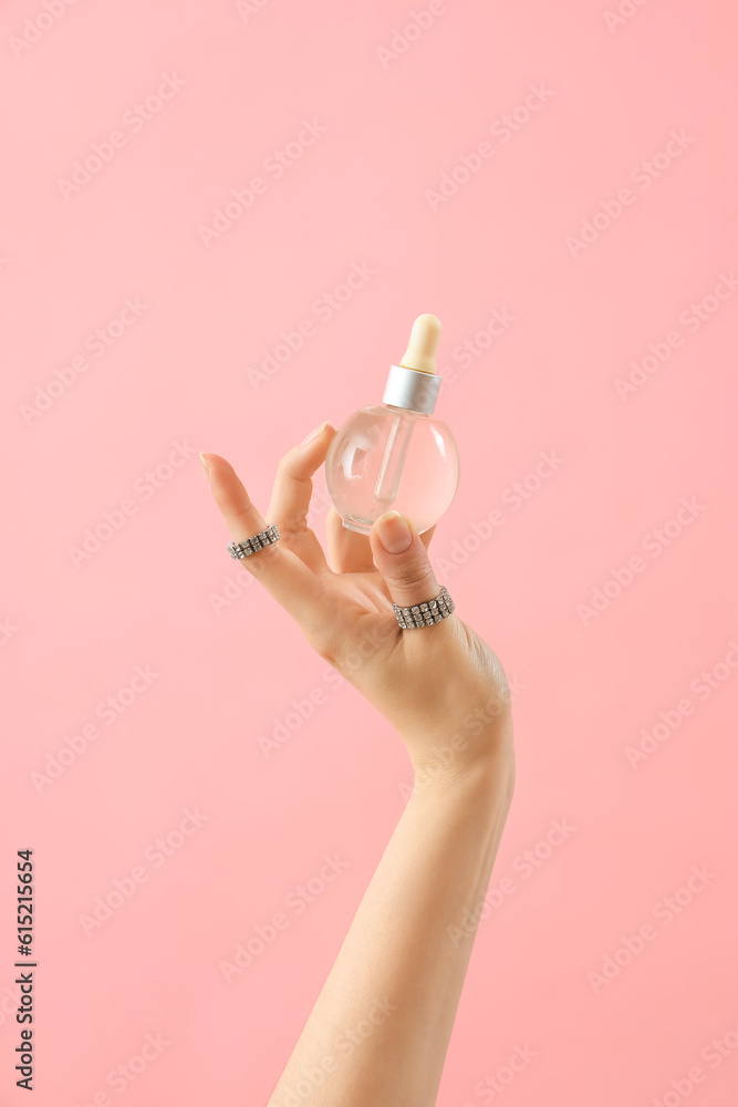 Hand holding cosmetic product on pink background