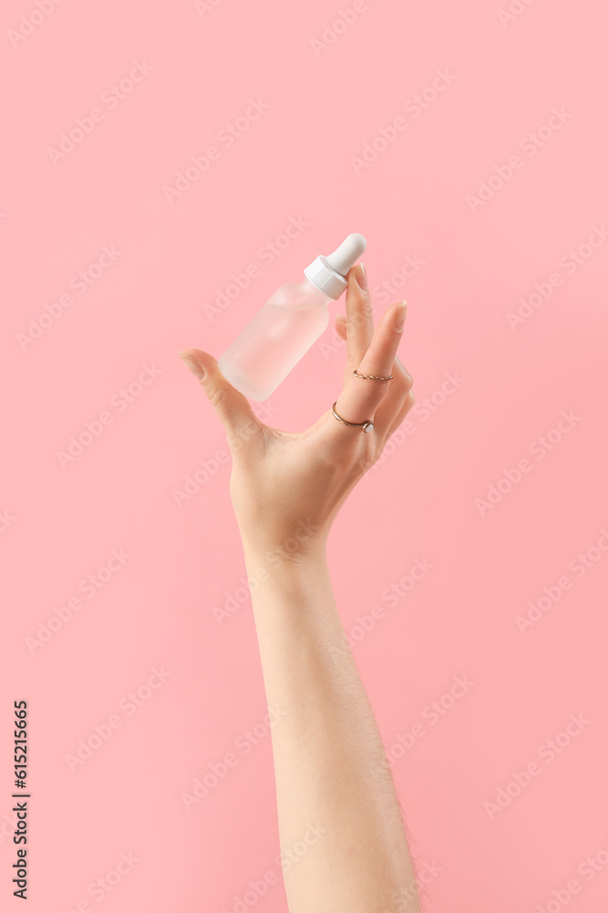 Hand holding cosmetic product on pink background