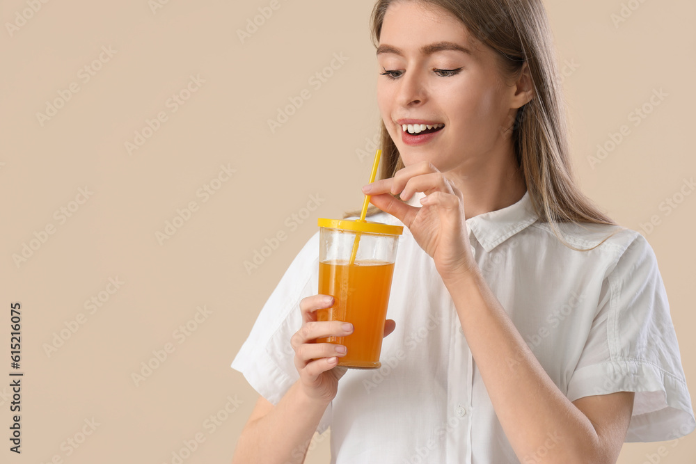 Young woman with glass of carrot juice on beige background, closeup