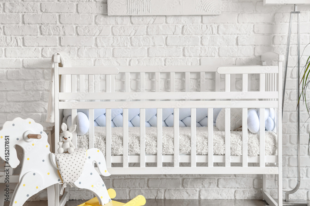 Baby crib with toys in interior of light bedroom