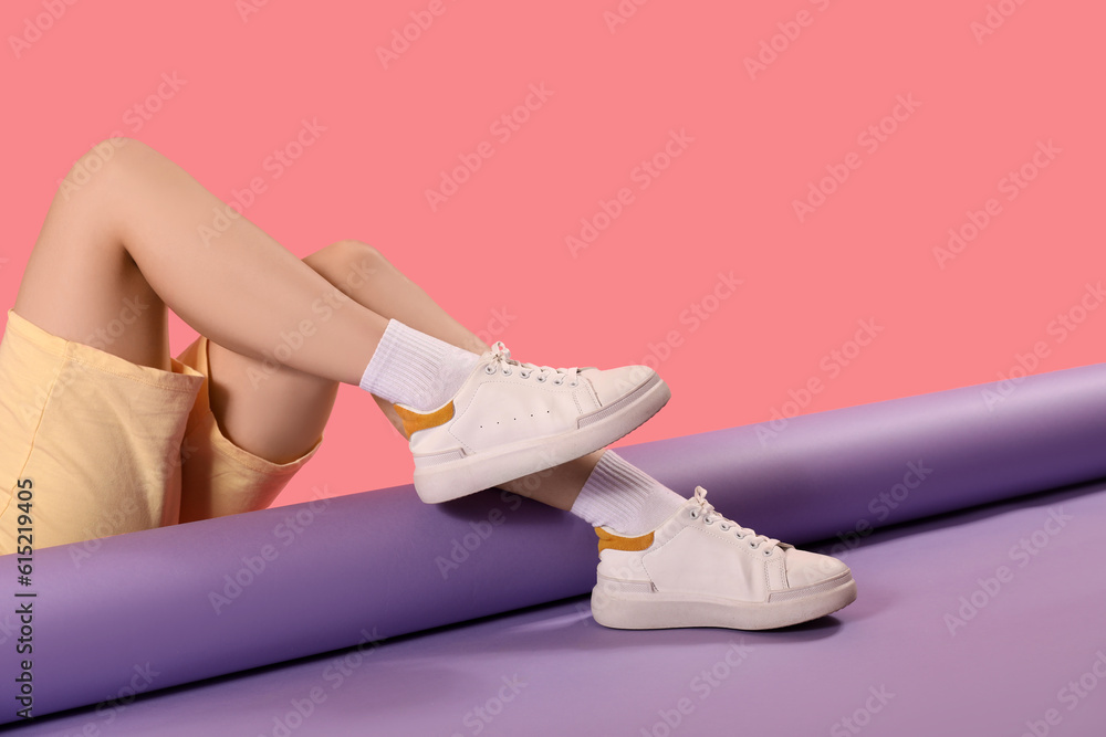 Female legs in stylish sneakers and socks on color background