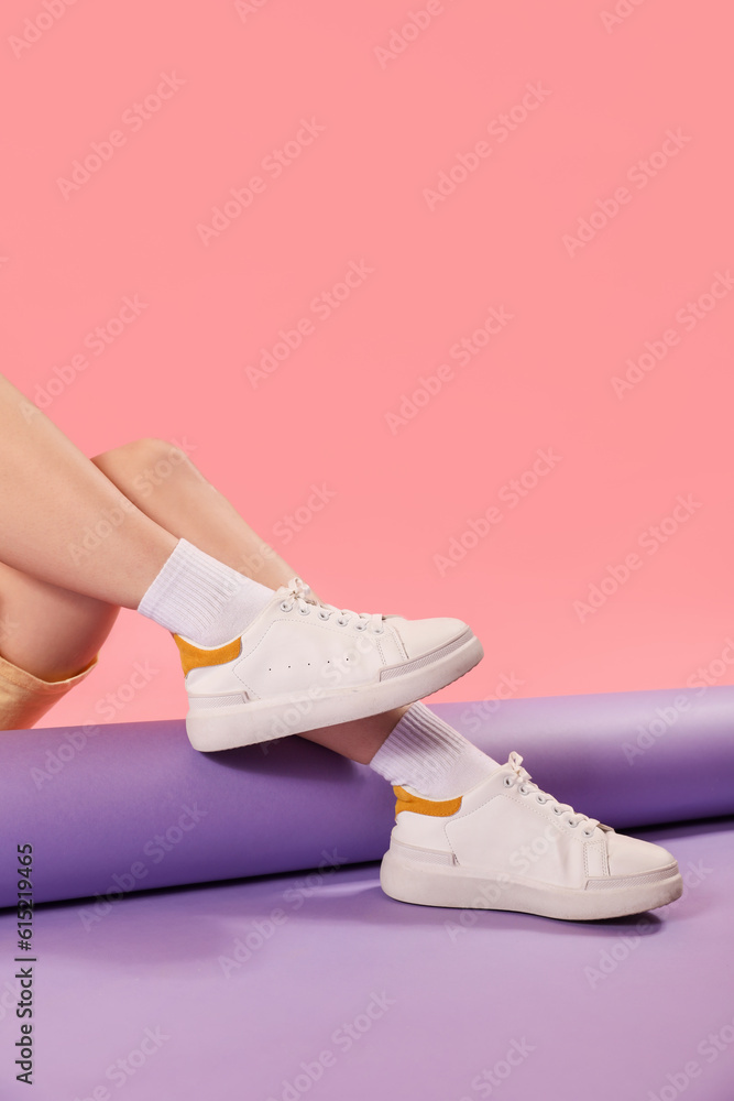 Female legs in stylish sneakers and socks on color background