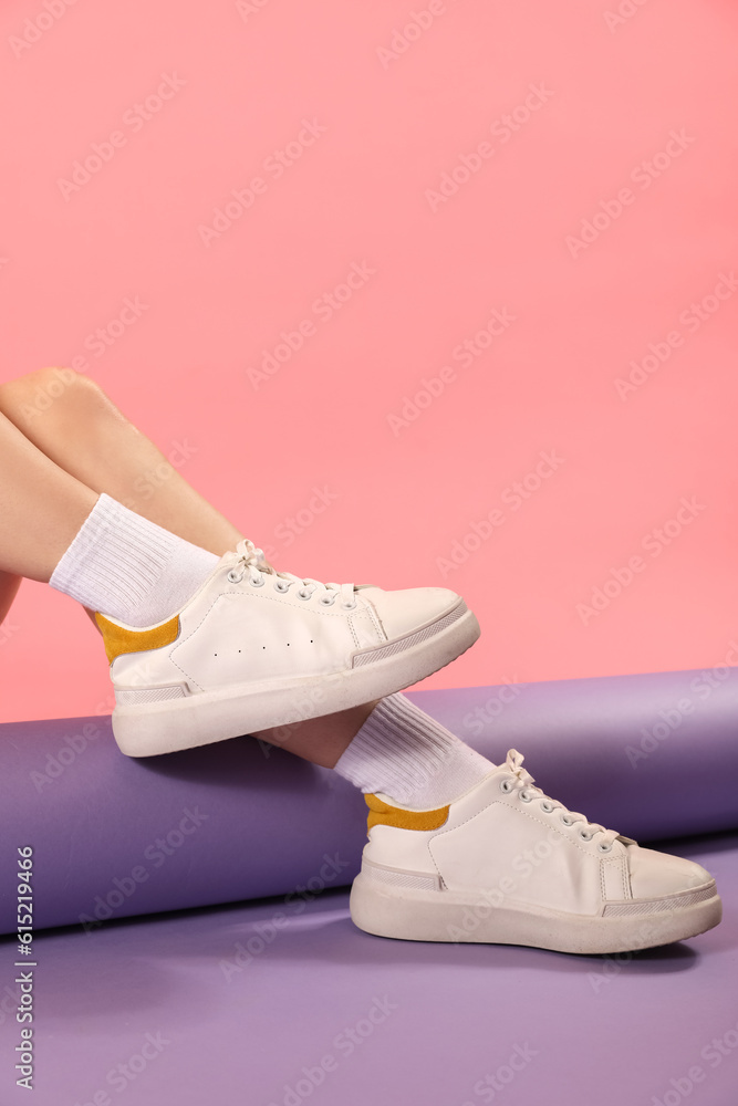 Female legs in stylish sneakers and socks on color background