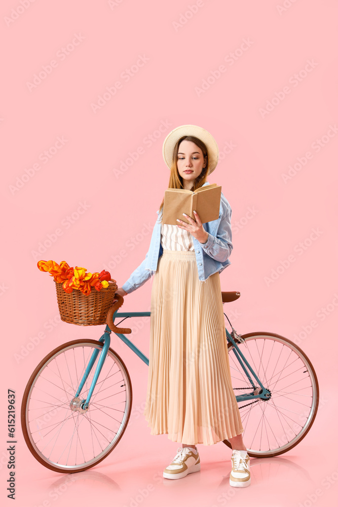 Young woman with bicycle on pink background