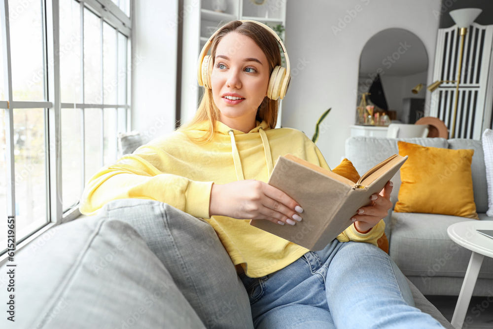 Female student in headphones reading book at home