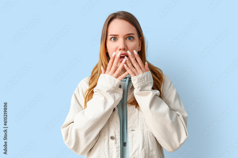 Shocked young woman on blue background