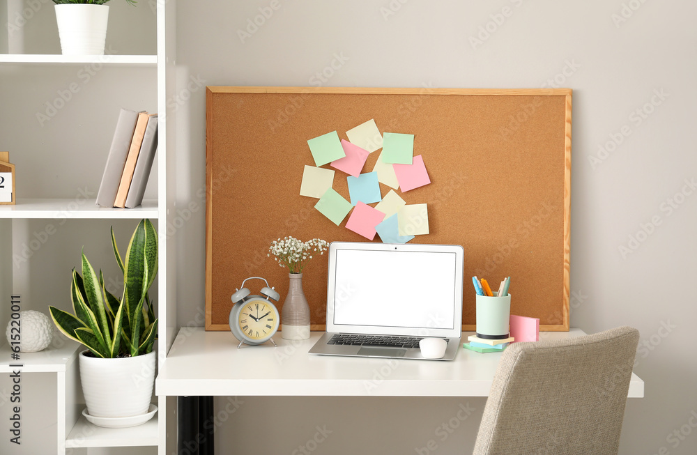 Board with sticky notes and laptop on table in room