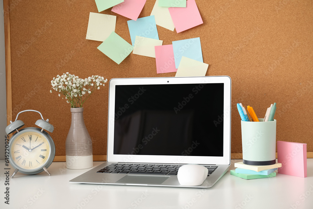 Board with sticky notes and laptop on table in room