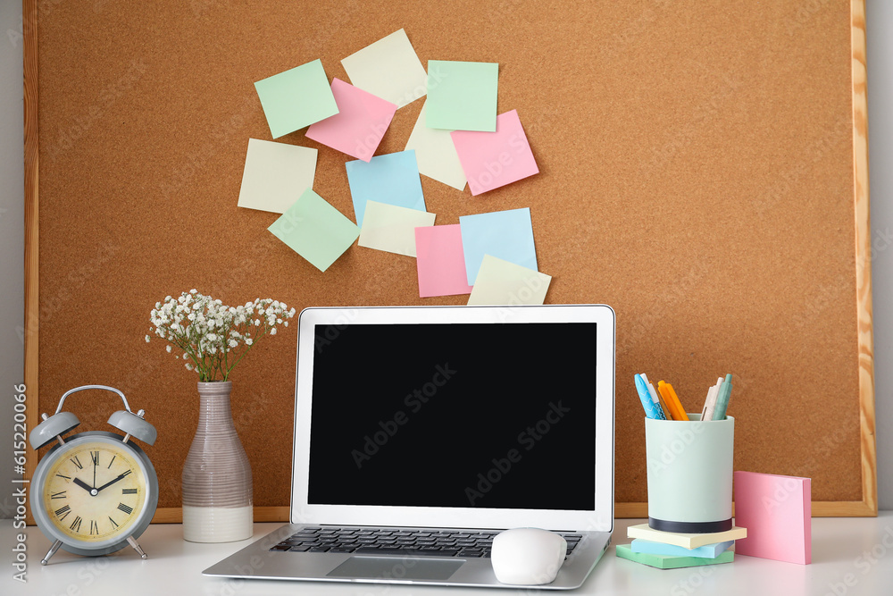 Board with sticky notes and laptop on table in room