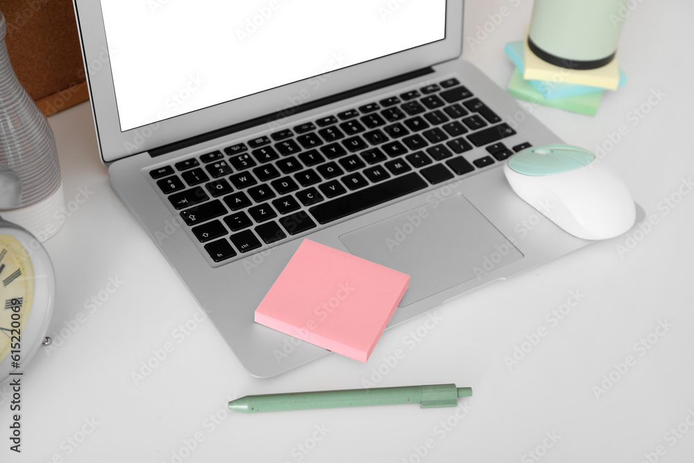 Laptop with sticky notes on white table