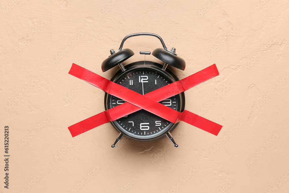 Alarm clock with cross made of adhesive tape on beige background